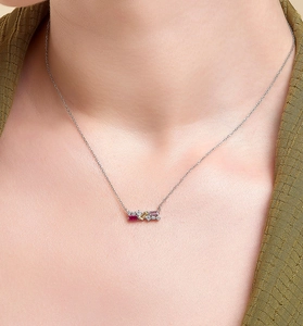 Close-up of model wearing a silver necklace with three multi-colored baguette gemstones