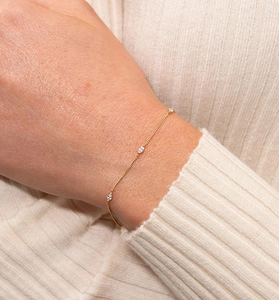 Close-up of minimalist gold bracelet with marquise-cut zircons on a knit sleeve