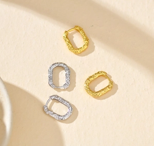 Macro shot of S925 sterling silver stamp on textured gold and silver oval hoop earrings