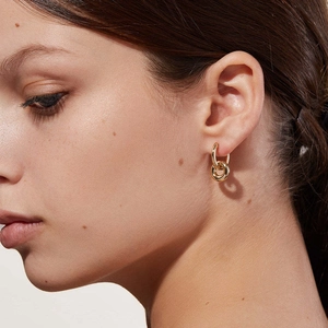 Detail of a woman wearing gold S925 sterling silver double-ring hoop earrings in a minimalist style