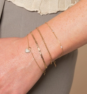 Close-up of a four-piece gold bracelet set with heart lock charm and zircon inlay