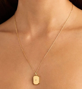 Close-up of a gold-toned rectangular locket necklace with a starburst pattern and gem