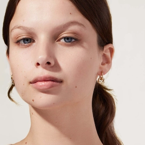 Polished 18K gold double hoop earrings worn by a model in a minimalist lifestyle setting