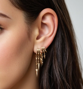Close-up of gold layered spike fringe earrings on model with polished metal finish