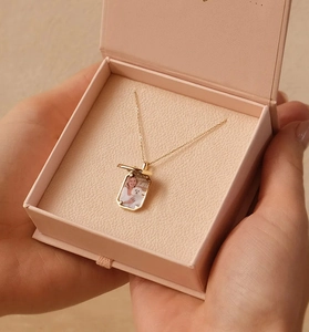 Square locket necklace in 18K gold featuring a personalized photo inside a pink gift box
