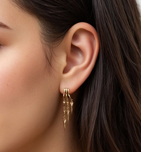 Close-up of gold layered cone tassel earrings worn by a model with detailed metallic shine