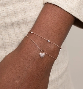 Close-up of rose gold bracelet set with heart lock charm and marquise zircon on wrist