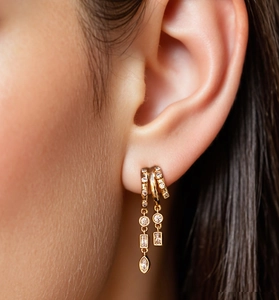 Macro detail of model wearing gold tiered drop earrings with sparkling zircon crystals