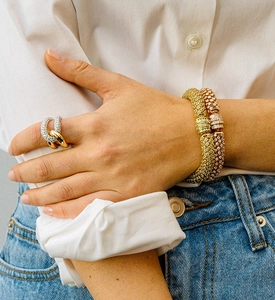 Close-up of luxury micro-paved diamond bangles and interlocking ring on female model
