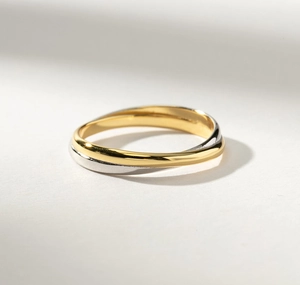 Détail macro des anneaux entrelacés bicolores or et argent d'une bague minimaliste chic