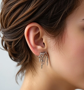 Macro shot of silver spike tassel earrings with layered rhinestone rings on model
