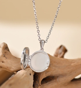 Macro shot of an open silver locket necklace on natural wood, showing interior details