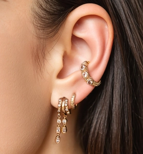 Detail of gold ear cuff and fringe drop earrings set with crystals on model's ear