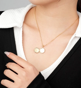 Detail of an open round golden locket necklace on a model showing inner photo space