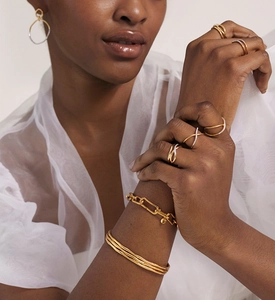 Close-up of gold geometric multilayer cross rings and chain bracelet on a female model