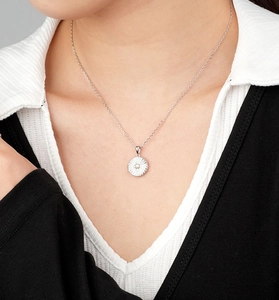 Detail of round starburst locket necklace with center pearl worn by model