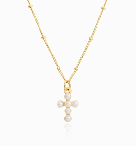 Macro view of gold chain necklace featuring small pearls forming a cross pendant