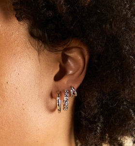 Close-up of three S925 silver hoop earrings with zircon stones on a female model
