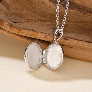 Octagram silver locket necklace with open photo compartment on textured wood background