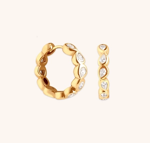 Macro detail of gold huggie earrings featuring pear-cut cubic zirconia in pavé setting