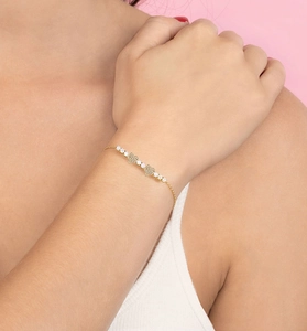 Detail of a dainty gold heart bracelet with pavé diamonds and opal beads on wrist
