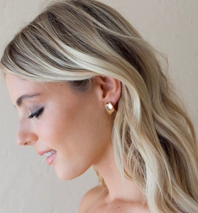 Close-up of elegant chunky gold-plated geometric hoop earrings worn on ear