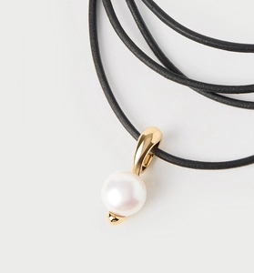 Vue macro d'un pendentif perle 8-9mm avec dorure sur un cordon en cuir noir fin