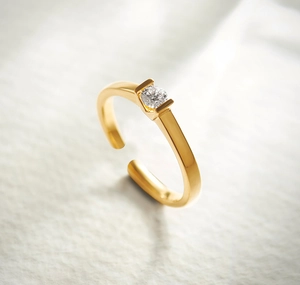 Macro shot of gold-plated open ring featuring a channel-set round solitaire stone