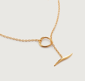 Detail einer minimalistischen goldenen Halskette mit poliertem T-Verschluss und Ringanhänger
