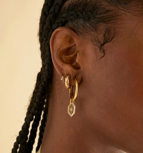 Detail of gold-plated earring set featuring starburst pendant and textured hoops on ear