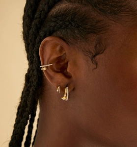 Detail of gold star drop earrings and cubic zirconia ear cuffs on model's ear