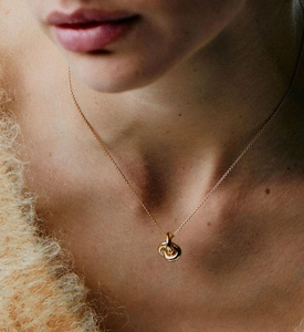 Close-up of interlocking double ring knot necklace on model in golden finish