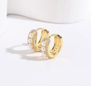 Détail de créoles en or 18 carats avec perles blanches et pierres de zircone cubique