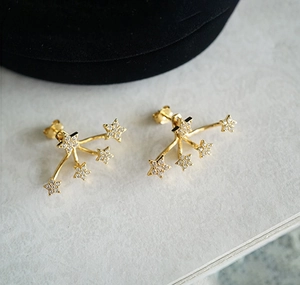 Close-up of gold S925 sterling silver star studs featuring shimmering cubic zirconia gems