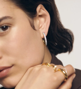 Gros plan de boucles d'oreilles créoles dorées en C avec zircons sur un mannequin