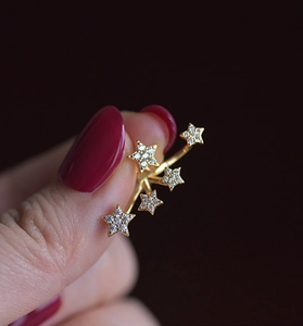 Macro shot of gold-plated five-star ring with pavé-set white zircons on finger