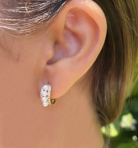 Détail de créoles dorées avec quatre perles et pavé de diamants portées à l'oreille