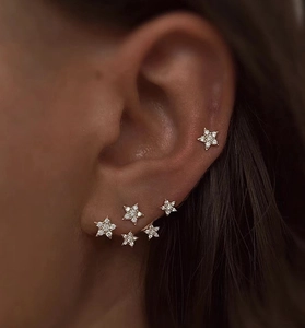 Close-up of star-shaped gold earrings with sparkling stones worn by a model