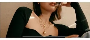 Dettaglio di una collana dorata a tre strati con pendente a goccia e orecchini a sfera