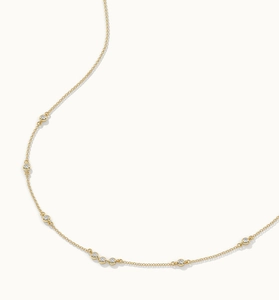 Détail du serti clos doré avec zircons ronds sur une chaîne fine au style minimaliste