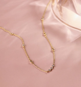 Détail du collier en argent doré avec zircons ronds sur tissu en soie rose