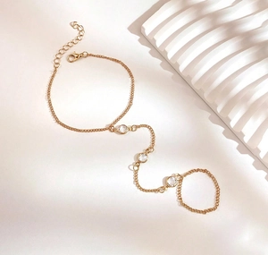 Dettaglio del bracciale ad anello dorato con tre zirconi rotondi su uno sfondo minimalista