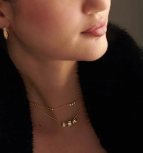 Détail d'un collier doré double épaisseur avec pendentifs géométriques carrés en diamant