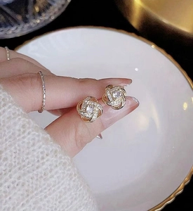 Detail view of gold clover stud earrings with paved zircons and a central diamond accent