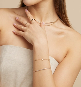 Détail d'un ensemble de bijoux coeur dorés superposés avec zircon brillant sur modèle