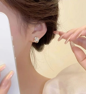 Detailed view of gold four-leaf clover earrings with zircon inlay worn on ear