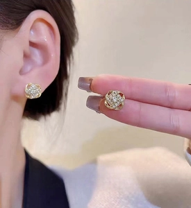 Detail of gold clover stud earrings with sparkling pavé zircons in a floral knot design