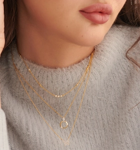 Gros plan d'un ensemble de colliers triples en or avec zircons et pendentif papillon