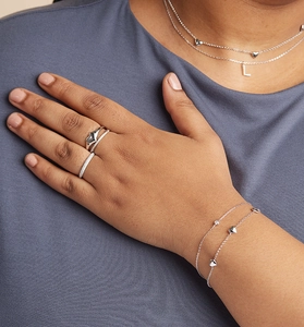 Gros plan d'un bracelet et collier cœur en argent S925 avec zircons portés par un modèle
