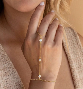 Dettaglio di un set bracciale ad anello dorato con tre cristalli bianchi tondi sulla mano